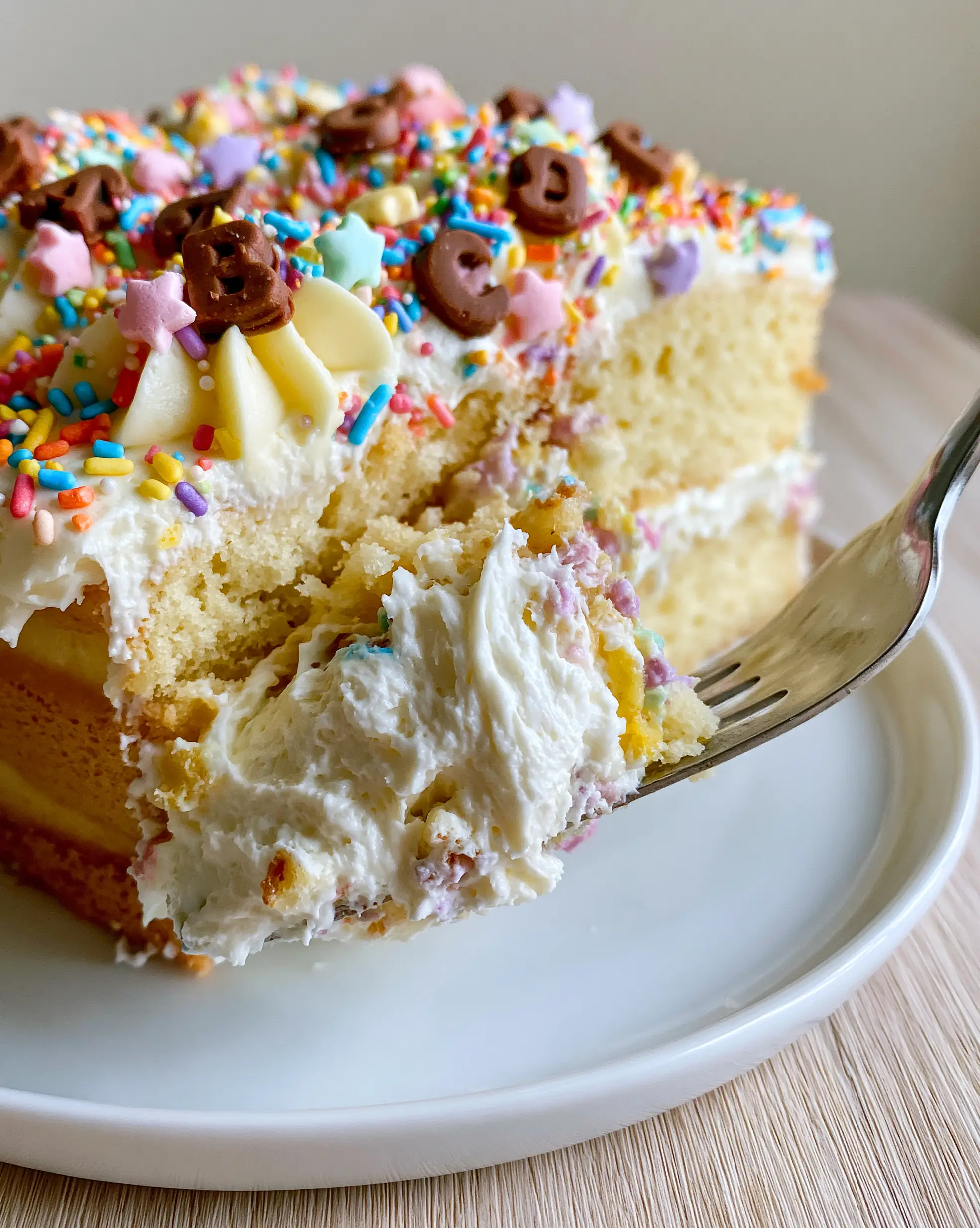 A close-up shot of an Einschulungskuchen slice being lifted by a silver server, showing a creamy pull of whipped cream.