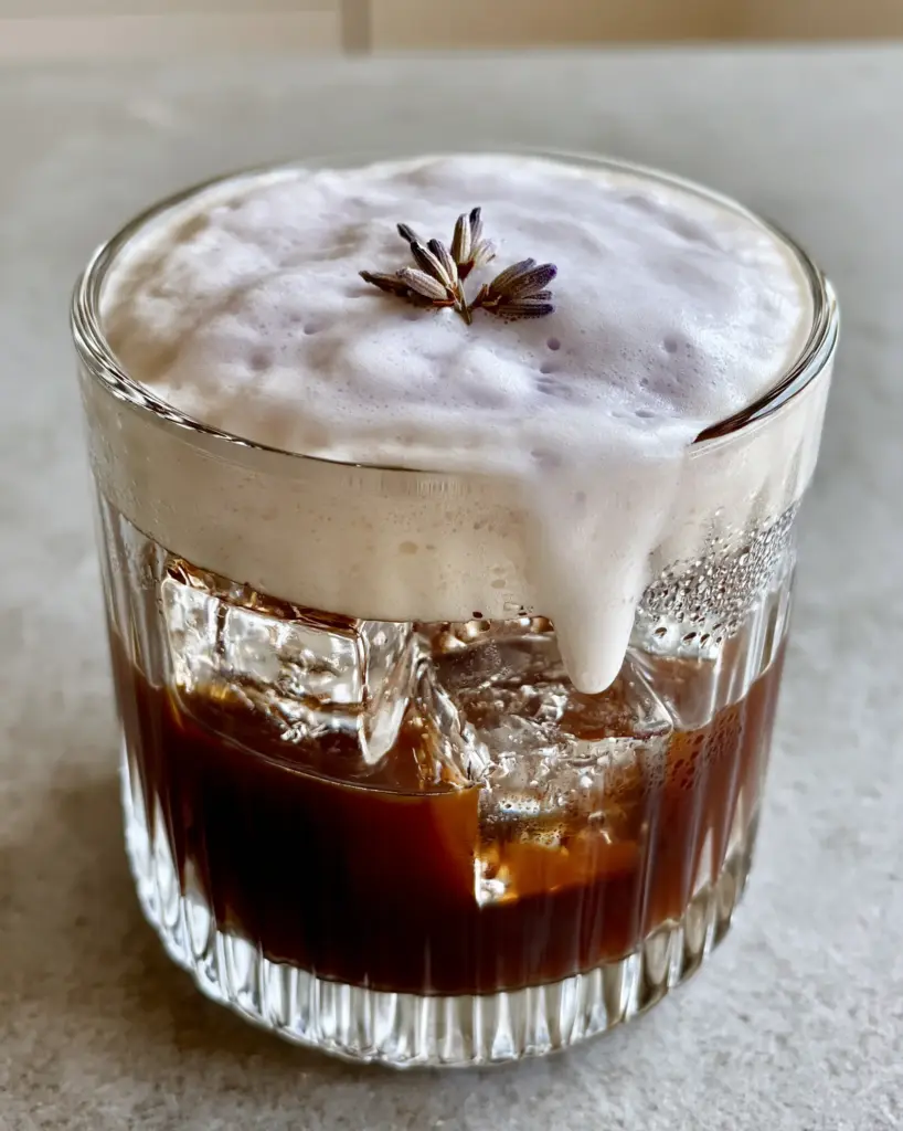 Lavender Cold Foam: The Ultimate Guide to Aesthetic Barista-Style Coffee 2 Close-up of thick, velvety lavender cold microfoam cascading down a glass of iced espresso. (Lavender Cold Foam)