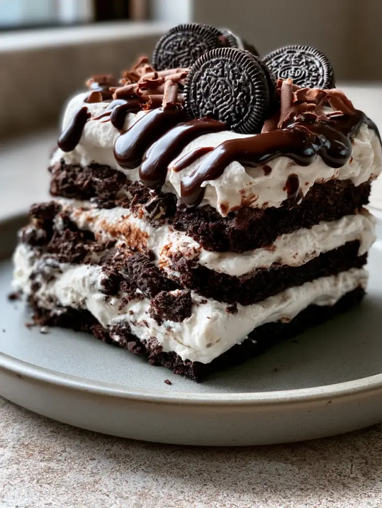 Oreo Cake: The Ultimate No-Bake Chocolate Layer Indulgence 2 Close up of Oreo cake slice with glossy dark chocolate drizzle and mini cookies.