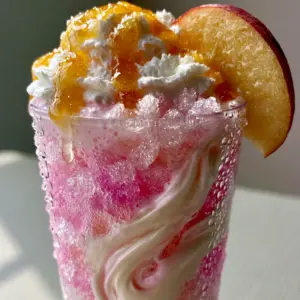 Close up of the physical layers in a Sonic Princess Peach drink showing pink fizzy soda and glistening crushed nugget ice.