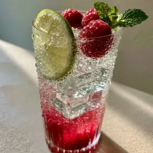 A smartphone photo showing realistic condensation on a ribbed glass filled with a layered summer mocktail. (summer mocktails)