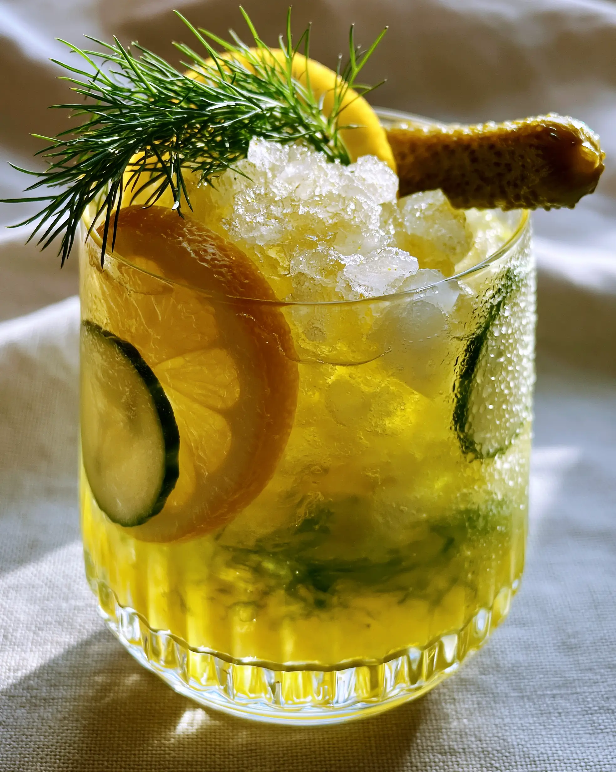 Close-up of Pickle Lemonade in a ribbed glass with visible green swirl of pickle juice and crushed ice. (Pickle Lemonade)