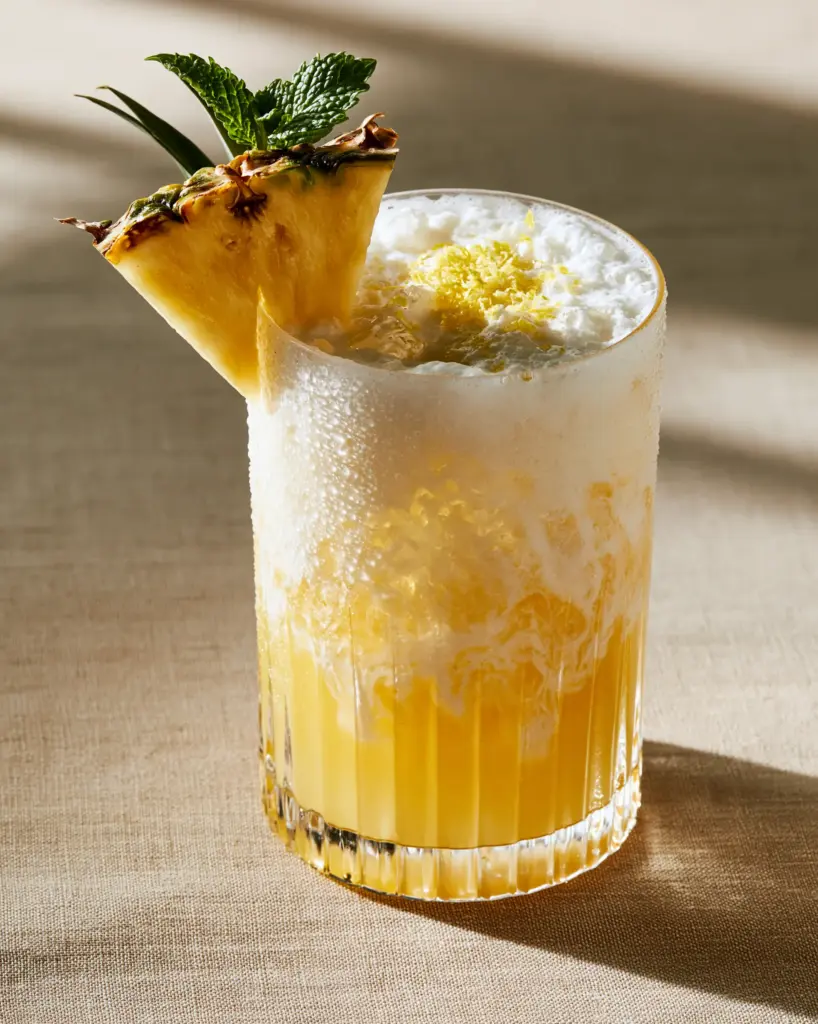 Close-up of the organic swirling gradients and lemon zest garnish on a coconut pineapple lemonade.