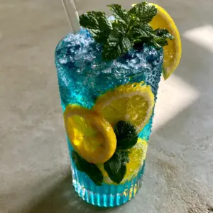 Close up of an electric-blue cocktail with vibrant yellow lemon wheels pressed against the glass. (blue curacao cocktails)